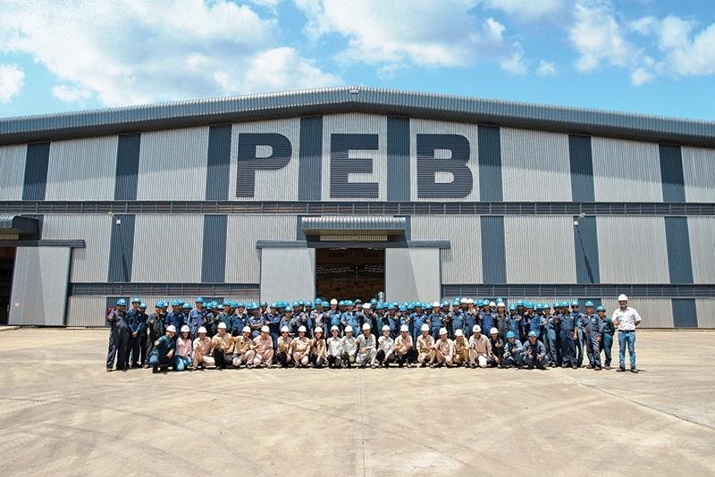 Employees of PEB steel buildings standing in front of the factory